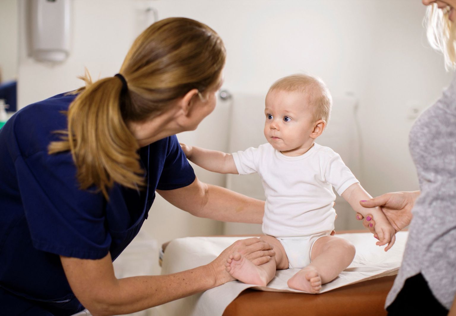 Bebis sitter själv på en BVC-mottagning och blir undersökt av sjuksköterska