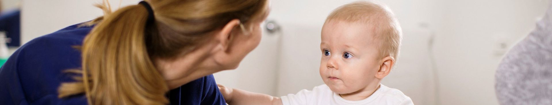 Bebis sitter själv på en BVC-mottagning och blir undersökt av sjuksköterska