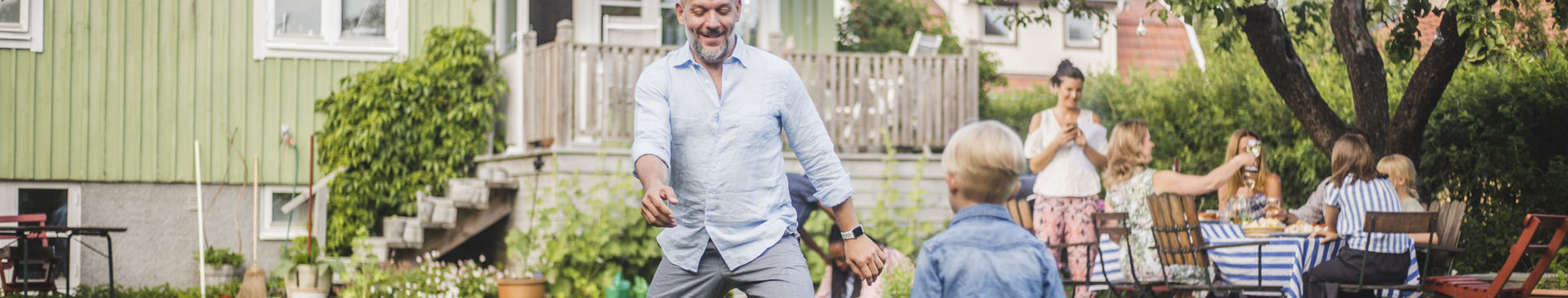 Pappa och pojke spelar fotboll på tomten utanför ett hus