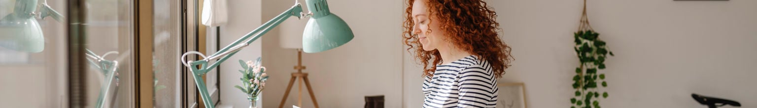 Kvinna sitter vid ett skrivbord och skriver på sin laptop